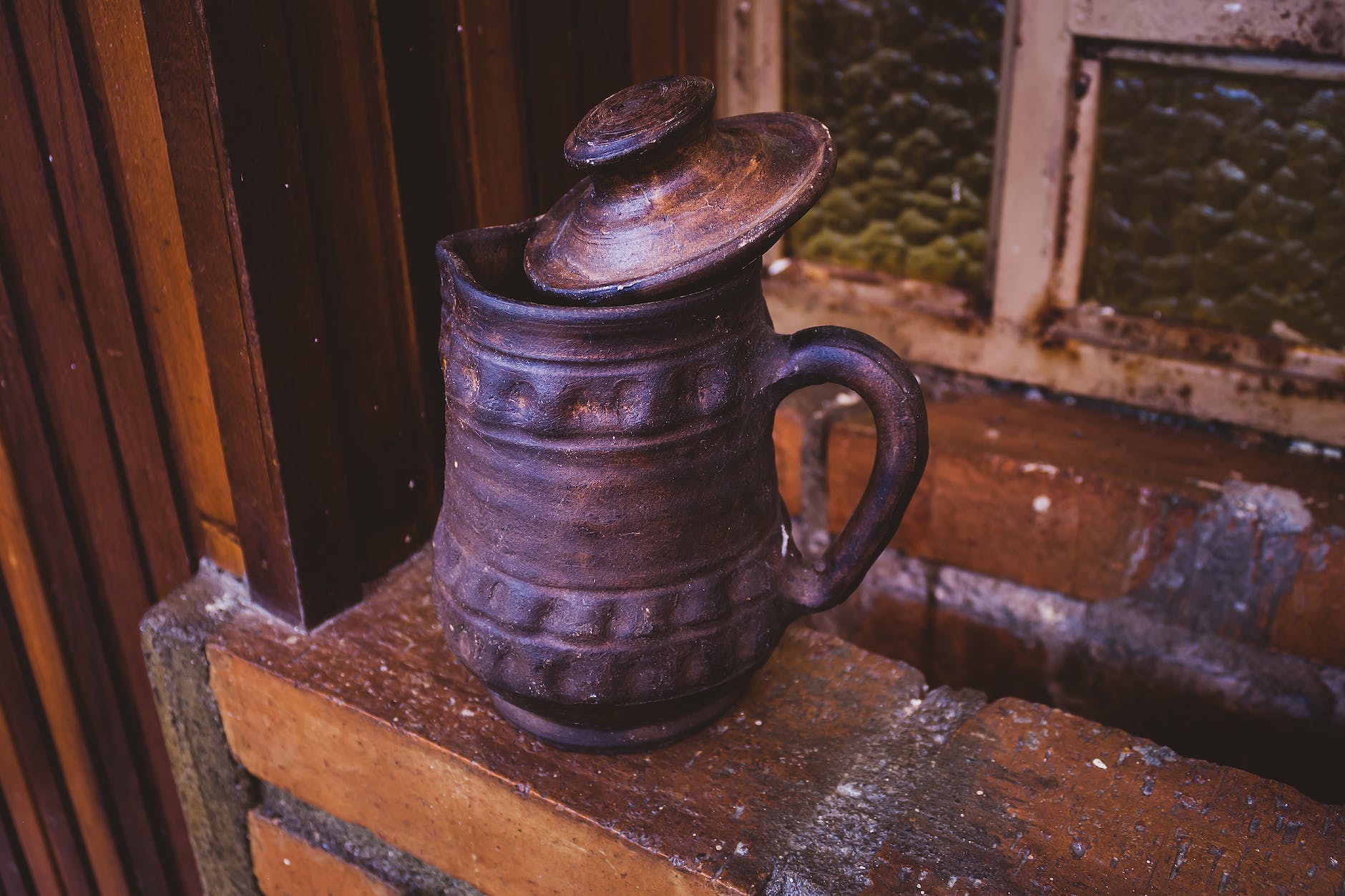 a brown pitcher sitting on a window sill